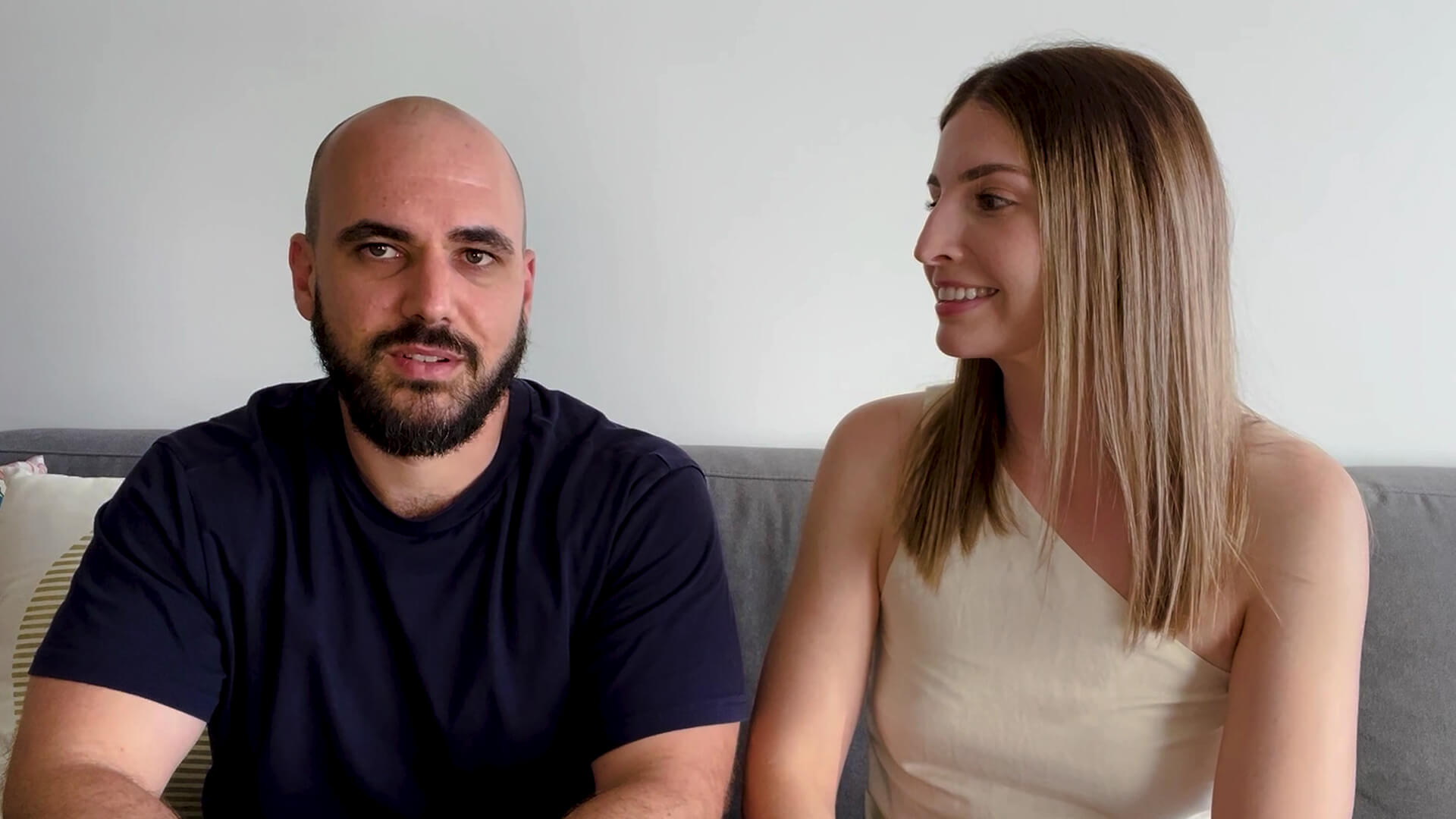 Photograph of a man and woman sitting on a couch within their new home.